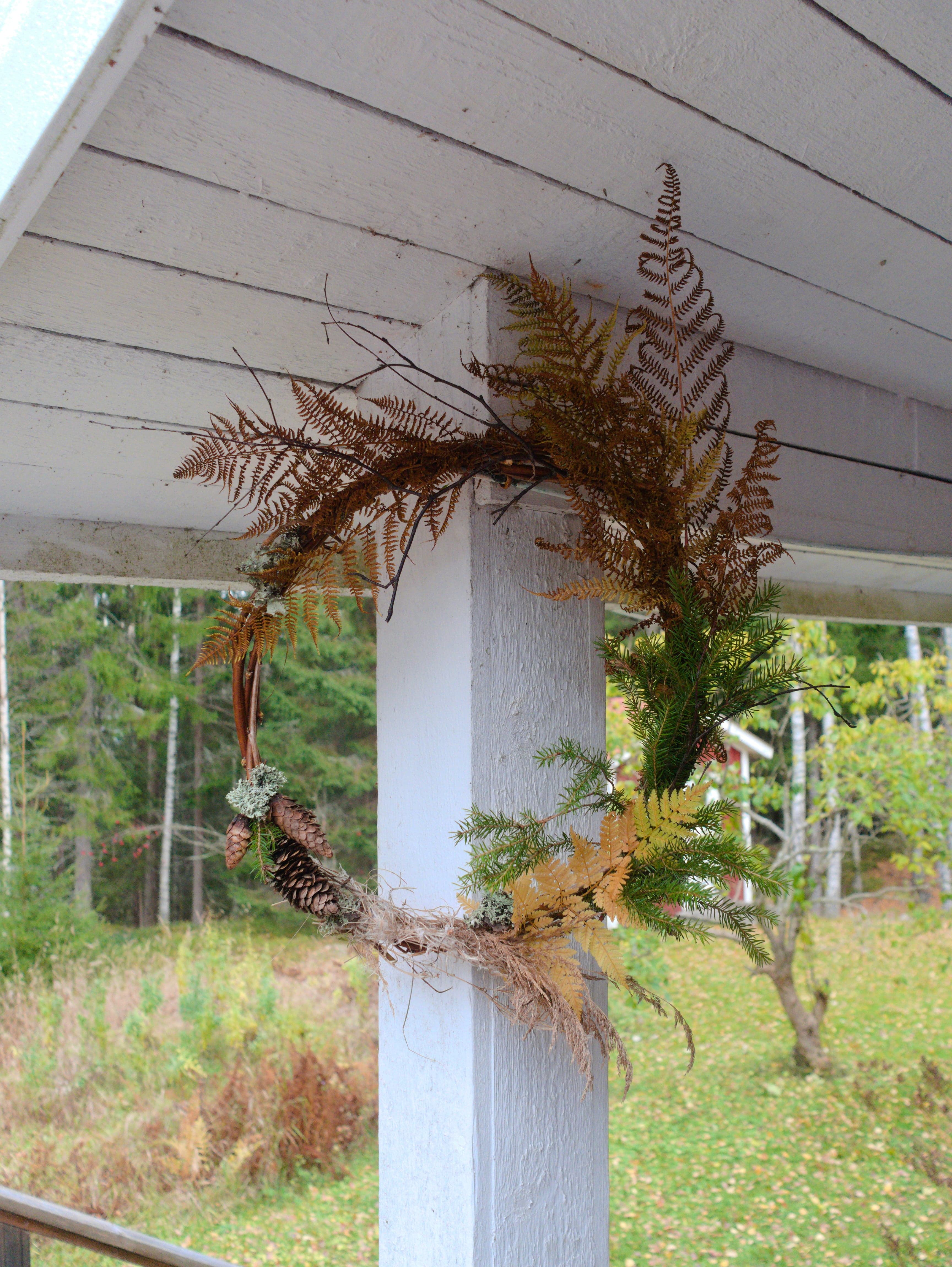 An autumn wreath simply decorated with pine cones and dry ferns and grasses.